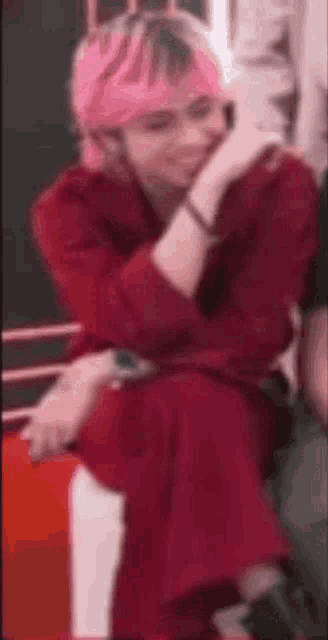 a woman with pink hair is sitting on a chair .