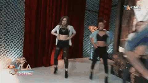 two women are dancing in front of a red curtain and a sign that says azteca on it