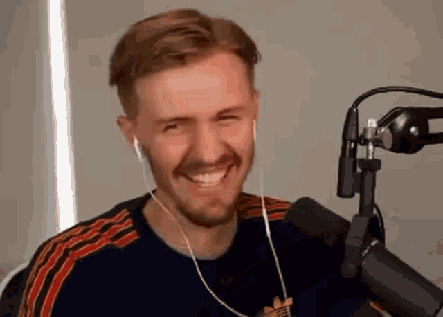 a man with a beard is smiling in front of a microphone .