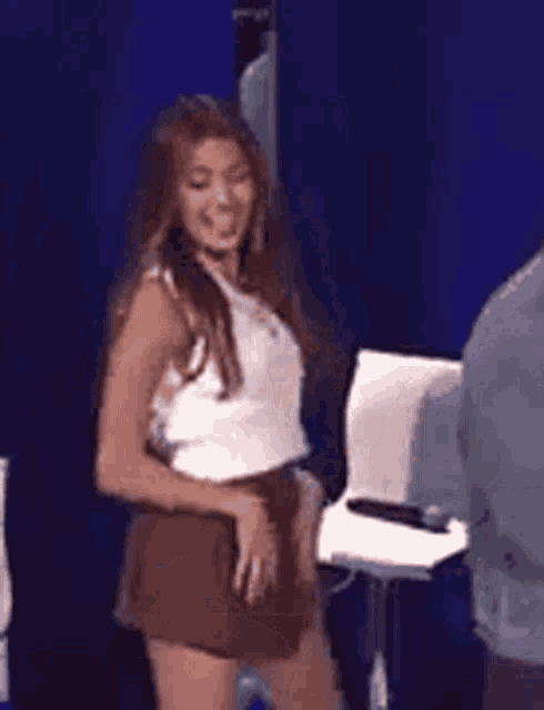 a woman in a white tank top and brown shorts is dancing in a room .