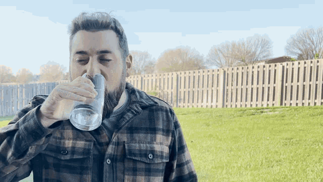 a man in a plaid shirt drinks from a glass
