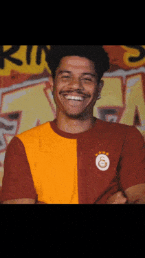 a man wearing a red and yellow shirt with the letter g on it smiles