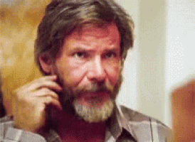 a man with a beard is talking on a cell phone while wearing a plaid shirt .