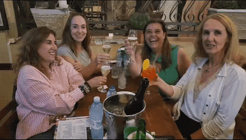 a group of women are sitting at a table with bottles of aquafina water
