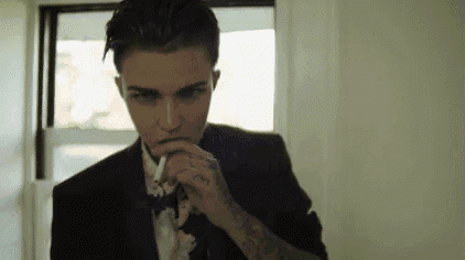 a man in a suit and tie is smoking a cigarette .