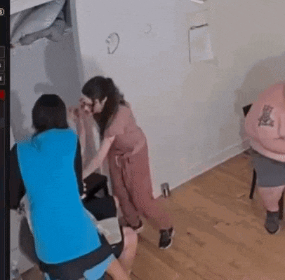 a group of people are standing in a room . one of the women has a tattoo on her back .