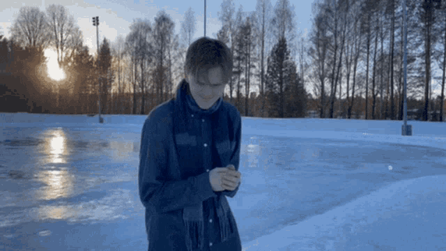 a man in a scarf stands in front of a snowy rink