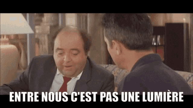 two men are sitting on a couch and one of them says entre nous c'est pas une lumière