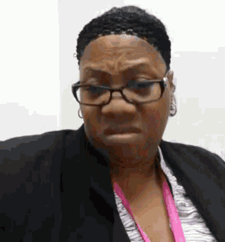 a woman wearing glasses and a pink lanyard is making a face .