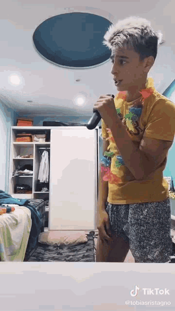 a young man is singing into a microphone while wearing a lei .