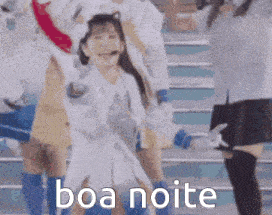 a group of girls are dancing on a stage with the words boa noite in the corner .