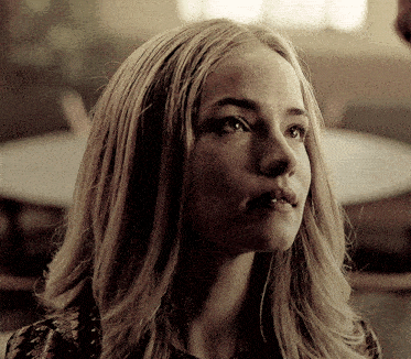 a woman with long blonde hair looks to the side
