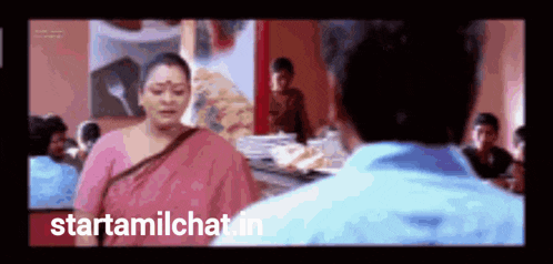 a woman in a pink saree is standing next to a man in a blue shirt in a restaurant ..