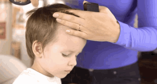 a woman combs the hair of a young boy