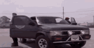 a man is standing next to a black pickup truck with its doors open .