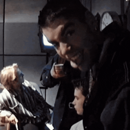 a group of people are sitting in a dark room with a clock on the wall