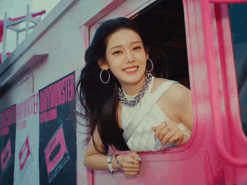 a woman is smiling while looking out of the window of a pink truck that says baby monster