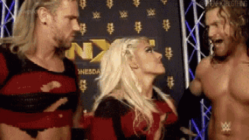 a group of wrestlers are standing next to each other in front of a sign that says nxt .