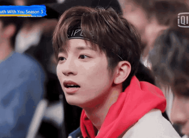 a young man wearing a headband and a red hoodie looks at something