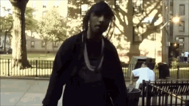 a man with dreadlocks is walking down a sidewalk
