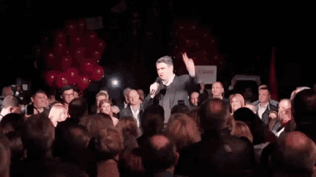 a man giving a peace sign in front of a crowd with signs that say coban