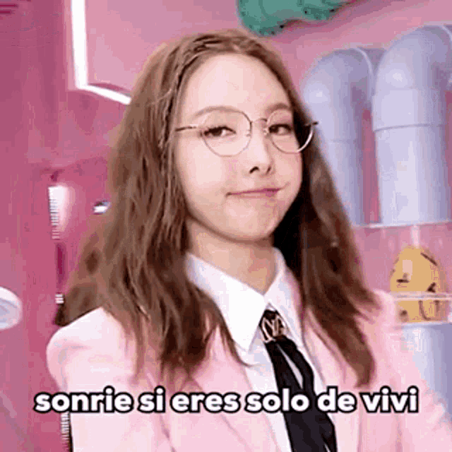 a girl wearing glasses and a pink jacket is smiling and says sonrie si eres solo de vivi
