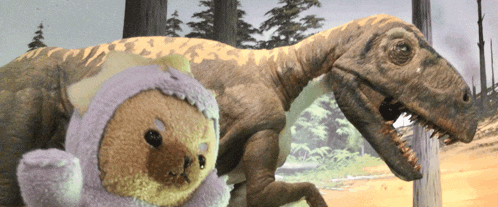 a stuffed animal is standing next to a dinosaur with trees in the background