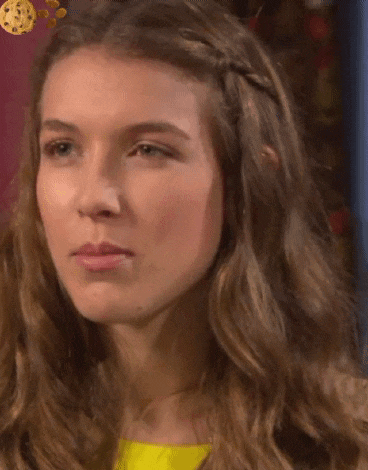 a close up of a woman 's face with a yellow shirt on and a braid in her hair .