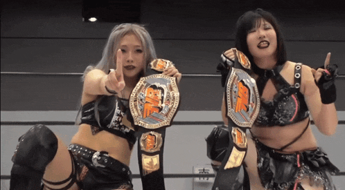 two female wrestlers are posing for a picture and one of them has a belt that says tke on it