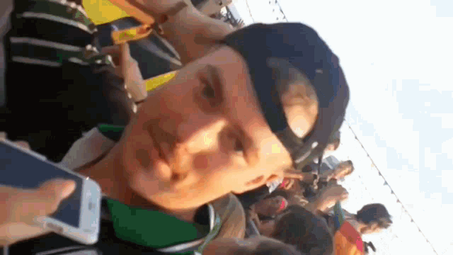 a man wearing a hat holds a cell phone in his hand