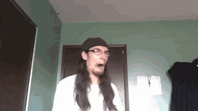 a man with long hair and glasses is wearing a hat and making a funny face