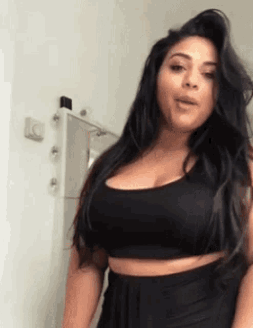 a woman with large breasts is standing in front of a mirror .