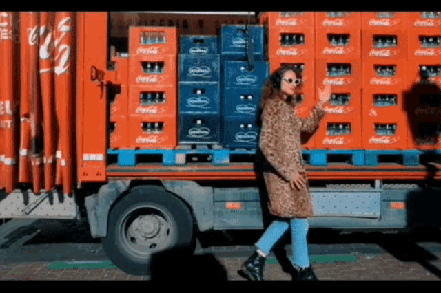a woman is standing in front of a truck full of coca cola crates