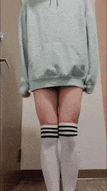 a person wearing a hoodie and knee high socks is standing in front of a door .