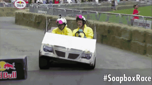 two men are driving a cardboard car in a soapbox race sponsored by red bull