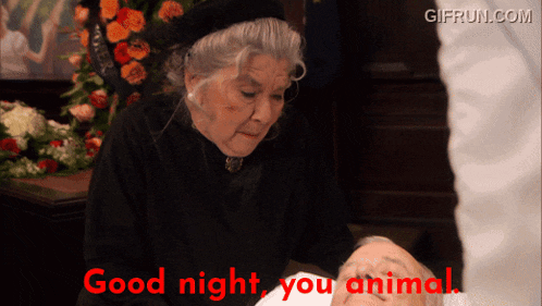 a woman standing next to a coffin with the words " good night you animal " written in red