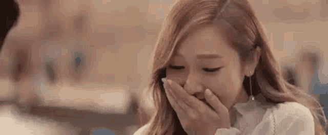 a close up of a woman covering her mouth with her hand .
