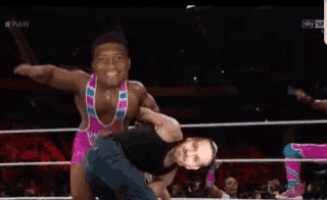 a wrestler is carrying another wrestler upside down in a ring