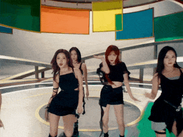 a group of young women are dancing in a circle in front of a colorful background