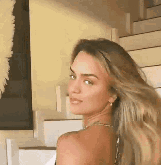 a woman with long hair is standing in front of a set of stairs .