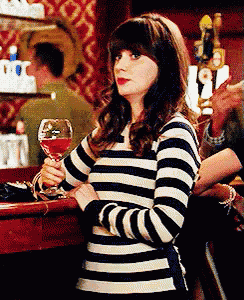 a woman in a striped shirt is holding a wine glass