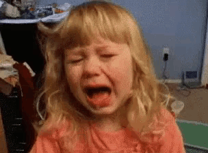 a little girl is crying with her eyes closed and her mouth open .