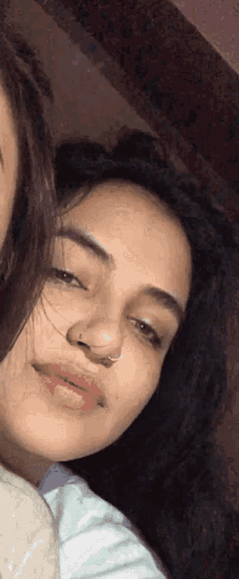 a woman with a nose ring is smiling and looking at the camera