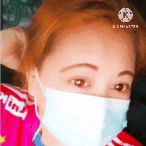 a woman wearing a face mask and a pink shirt is looking at the camera .