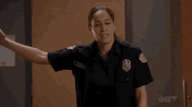 a woman in a firefighter uniform is standing in front of a door with her arm outstretched