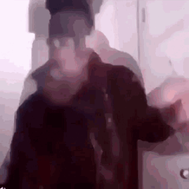 a blurry picture of a man standing in front of a door .