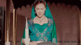 a woman in a green dress is standing in front of a statue