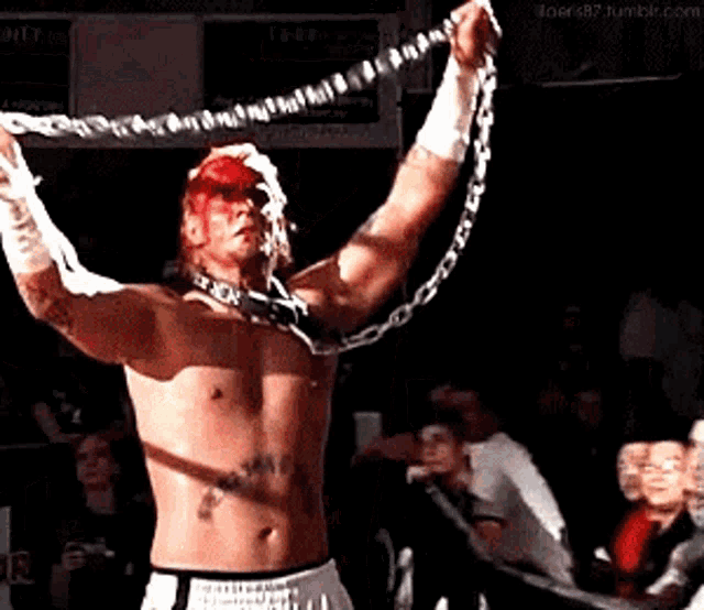 a man without a shirt is holding a chain over his head .