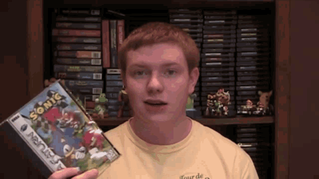 a man in a yellow shirt is holding a sonic game
