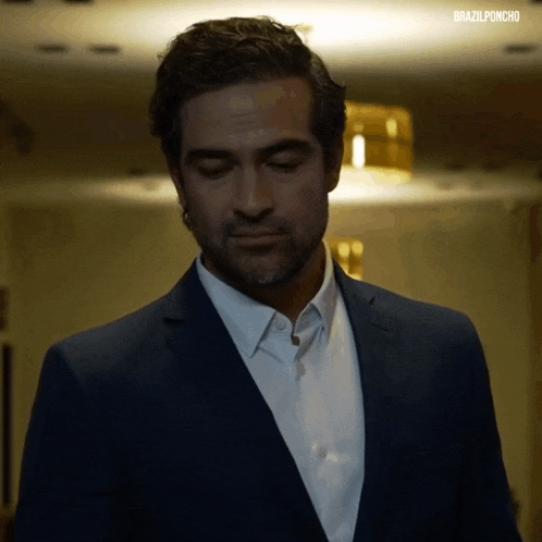 a man in a suit and white shirt is walking down a hallway with the words brazilponcho on the bottom